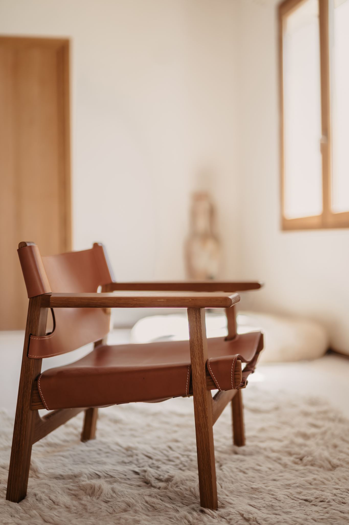 Fauteuil en cuir et bois sur tapis berbère, décoration intérieure épurée